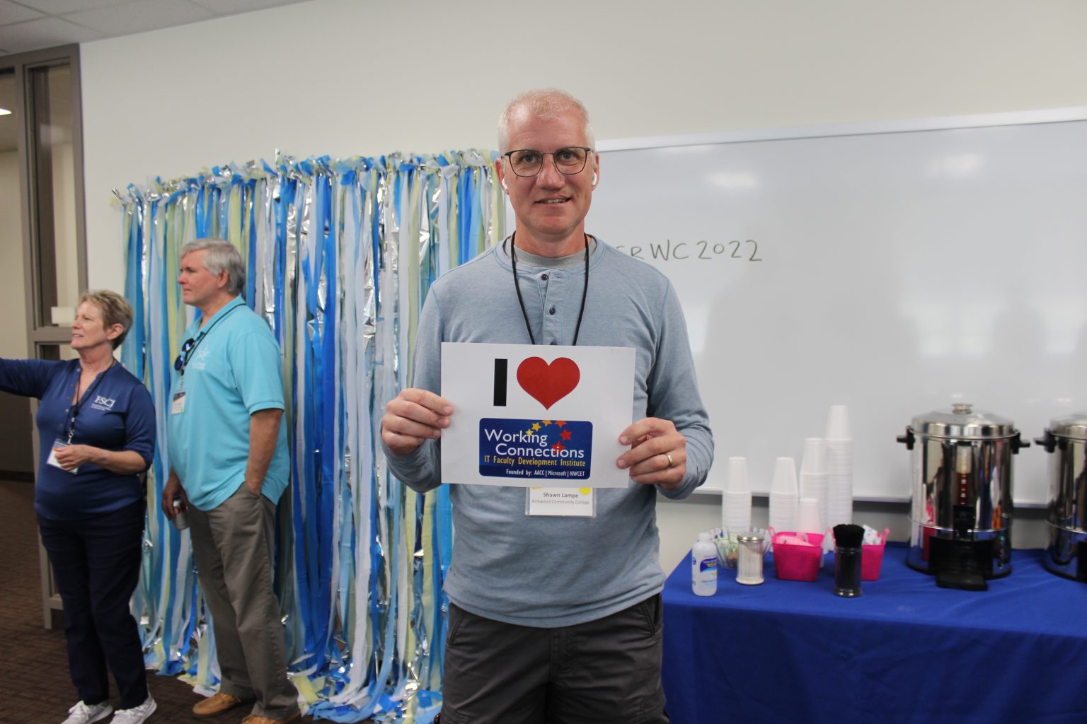 A Caucasian man in a blue shirt holding a sign with that says I (heart symbol) Working Connections. 