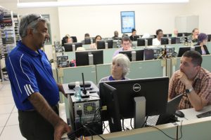 Faculty attendees at Summer Working Connections in July 2019 talk with their track instructor in a Collin College PC lab classroom.