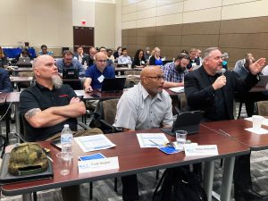 Employer members of the National CTC's BILT (Business and Industry Leadership Team) attend a job skills vote meeting.  Behind them in the conferene room are faculty and administrator attendees at the BILT Summit workshop.