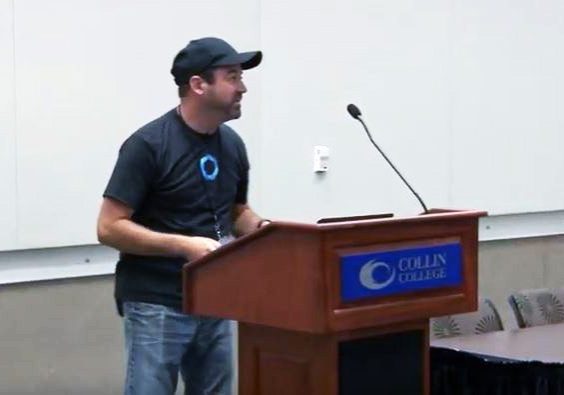 Presenter stands at Collin College podium - screenshot from the YouTube clip.